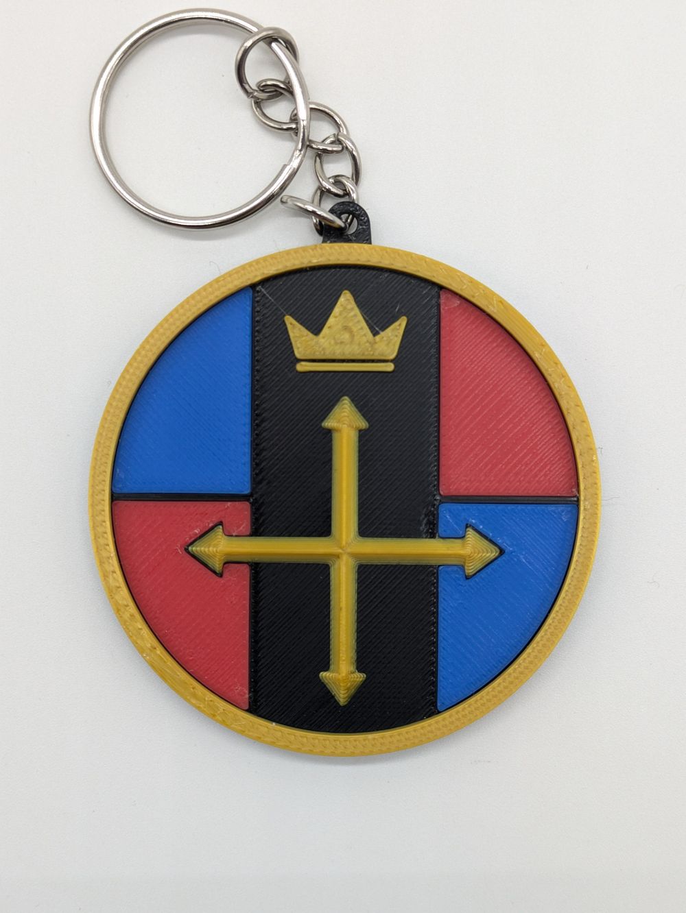 A key ring that looks like a stylized lion key from the old Voltron series. It's printed in different colors, like gold for the rim, the crown, and the cross in the middle. 