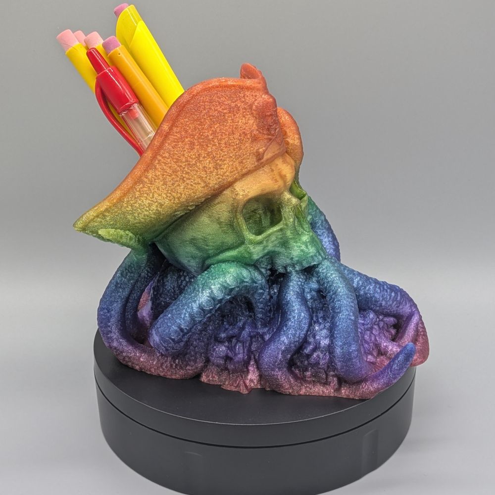 A 3D printed rainbow pen cup in the shape of a pirate skull with squid/octopus tentacles coming out of the bottom and forming the base.