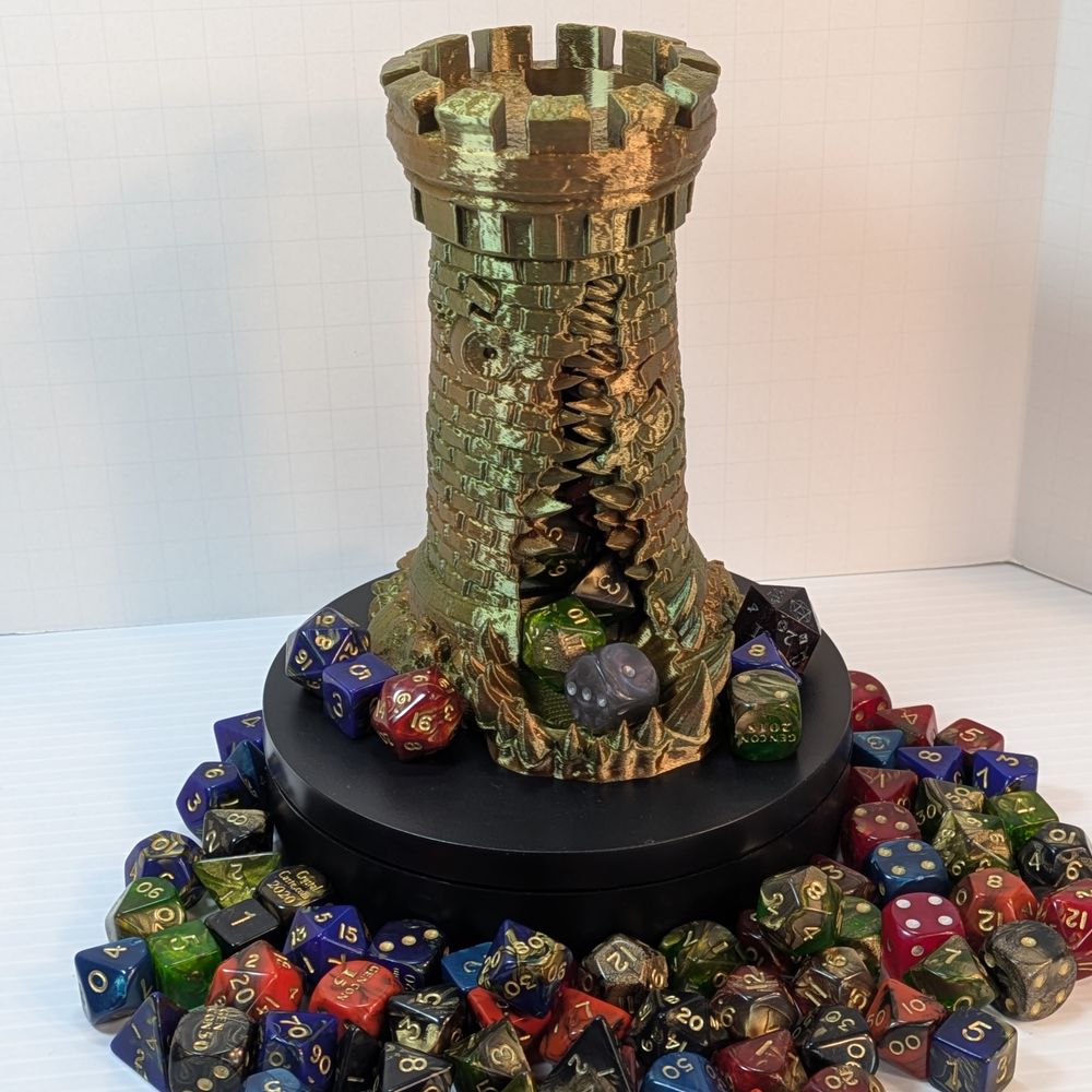 A 3D printed dice tower in the shape of a standard stone tower. This tower is in a shiny earth-tone filament, and has a large gaping maw up the side, in between two windows that look like eyes.