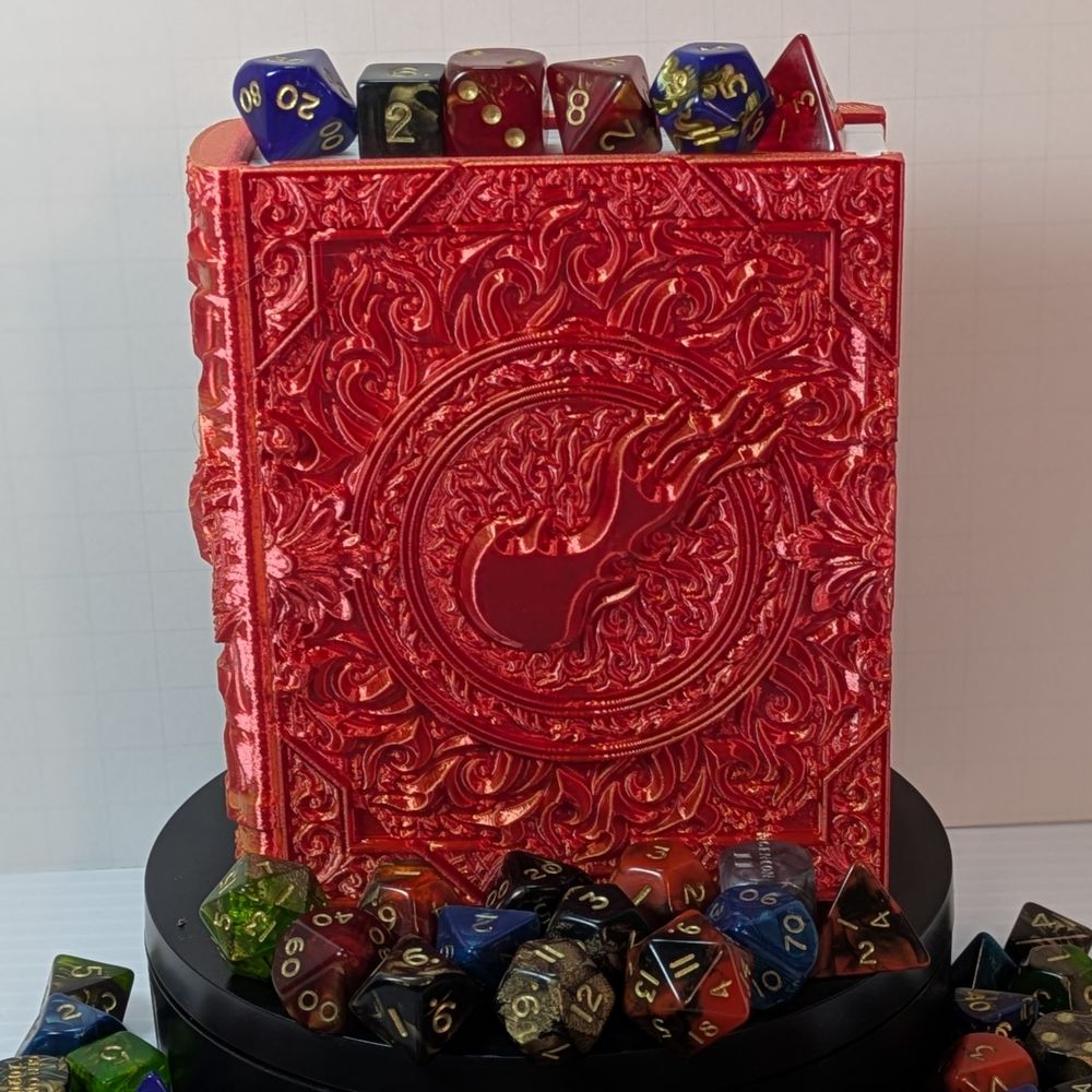 A 3D printed box that's shaped like a tome with fancy scrollwork and a fall of flame on the cover. It's made out of a shiny red/yellow filament, and it's surrounded by dice.